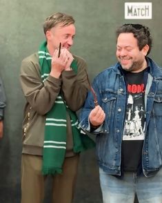 two men standing next to each other and laughing