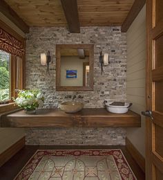 a bathroom with a stone wall and wood trim around the sink, along with a rug on the floor