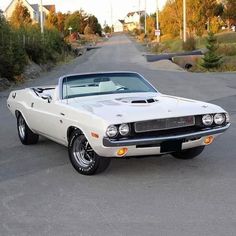 a white muscle car parked in a parking lot