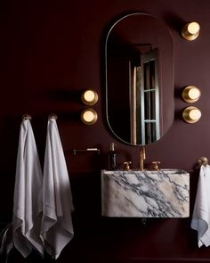 a bathroom with marble sink, mirror and towel rack in dark red color scheme on the wall