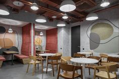 an empty restaurant with round tables and wooden chairs, painted on the wall behind them