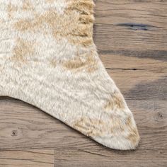 a brown and white cowhide rug on top of a wooden floor with wood planks