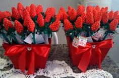 two red buckets filled with red flowers on top of a lace doily covered table