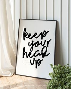 a black and white poster with the words keep your head up next to a potted plant