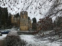 a castle in the middle of winter with snow on the ground and cars parked outside