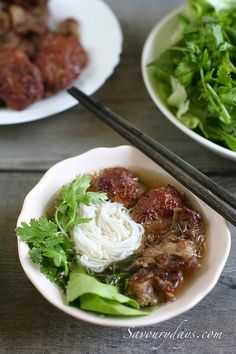 two bowls filled with meat and veggies next to chopsticks on a table