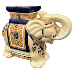 an elephant figurine sitting next to a blue and gold vase on a white background