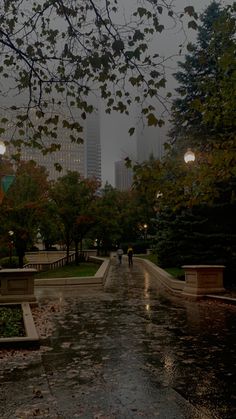 two people are walking down the street in the rain