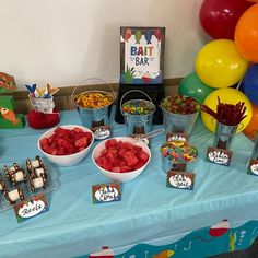 a table topped with lots of desserts and candy bar items on top of a blue cloth covered table