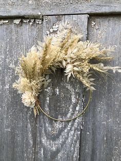 dried flowers are arranged on the side of a wooden door with metal ring around it