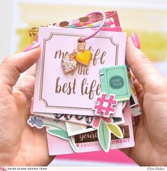 a person holding a pink card with lots of stickers on it that says, mom life is the best life