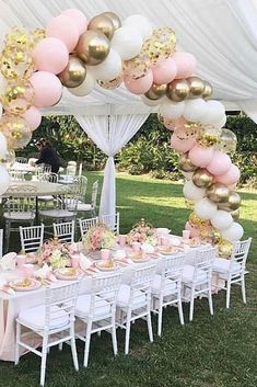 a table set up for a party with pink and gold balloons