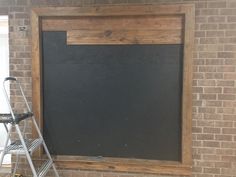 a brick wall with a blackboard and two ladders