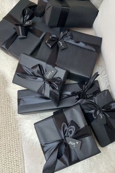 several black boxes with bows on them sitting on a white blanket in front of a couch