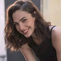 a young woman smiling and posing for the camera with her hand on her hip while wearing a black tank top