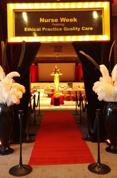 a red carpeted hallway leading to an entrance with black vases filled with flowers