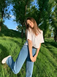 a woman standing in the grass with her legs spread out and looking at the camera