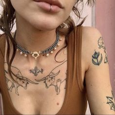 a woman with tattoos on her chest wearing a brown tank top and silver chain necklace