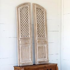 an old wooden cabinet with two doors on the top and bottom, in front of a white wall