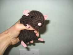 a hand holding a small stuffed animal in it's right hand, with pink ears