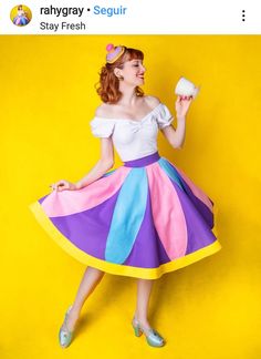 a woman in a colorful dress is holding a cupcake and posing for the camera