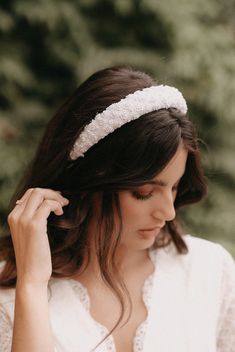 a woman wearing a headband and holding her hair in one hand while looking down