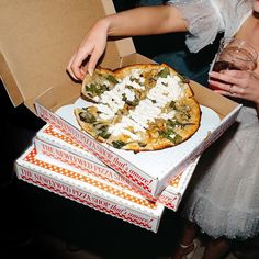 a woman is holding a pizza in a box