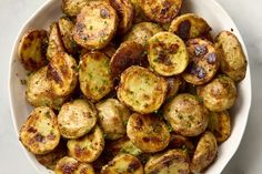 a white bowl filled with cooked potatoes on top of a table