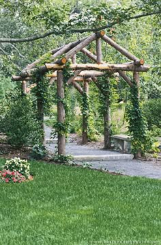 a wooden pergoline sitting in the middle of a lush green yard with flowers