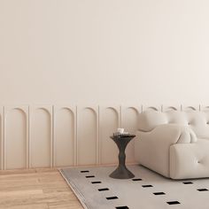 a white couch sitting on top of a hard wood floor next to a table with a candle