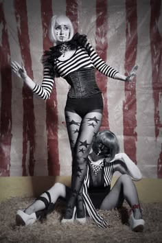 two women dressed in black and white are sitting on the ground next to an american flag