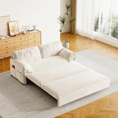 a white couch sitting on top of a hard wood floor next to a wooden dresser