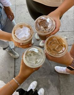 four people are holding their cups with drinks in them