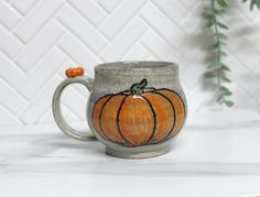 a ceramic mug with a painted pumpkin on it