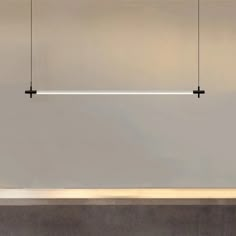 three lights hanging from the ceiling in a room with concrete flooring and walls behind them