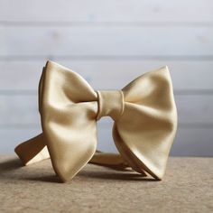 "Oversized Bow Tie in Champagne Gold Satin. Pre-tied and adjustable strap. Bow tie size - Width: 12 cm /4,7\" | Height: 10 cm / 3.93'' The adjustable strap takes it to 21\" in length, making it a great accessory that can be adjusted for comfort and fit or given as a gift if you are unsure of neck size. Perfect for formal or causal use. **bowties are shipped in a small shipping box to keep them from being damaged**" Luxury Bow Ties For Formal Occasions, Classic Luxury Bow Tie For Semi-formal Occasions, Luxury Classic Bow With Ties, Luxury Dapper Satin Bow, Dapper Gold Bow Tie For Formal Occasions, Gold Dapper Bow Tie For Formal Occasions, Classic Adjustable Bow Ties, Classic Gold Bow With Bow Tie Back, Gold Bow With Tie Back For Wedding