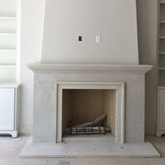 an empty living room with a fireplace and bookshelves in the corner, all white