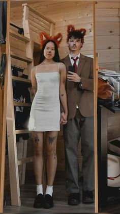 a man and woman standing in front of a wooden ladder with fake hair on their head