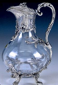 an ornate glass pitcher is sitting on a table with silver trimming and filigrees