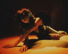 a woman laying on top of a bed in the dark