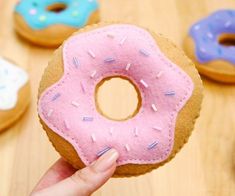 a person holding up a doughnut with sprinkles on it in front of other donuts