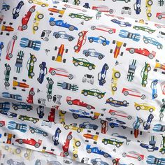 a white sheet with cars and trucks printed on it, sitting next to a pillow