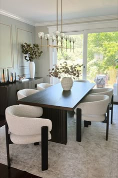 a dining room table with chairs and a vase on it