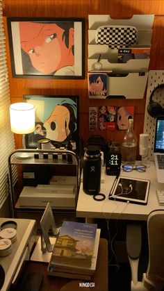 a desk with a laptop computer and various other items on it, along with posters