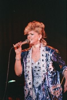 a woman standing in front of a microphone on stage