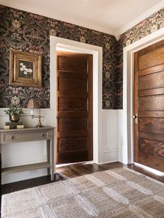 two wooden doors in a room with floral wallpaper and rugs on the floor