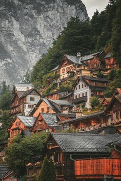 an alpine village with mountains in the back ground and houses on the top of it