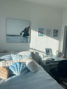 a bedroom with a bed, desk and pictures on the wall above it is shown