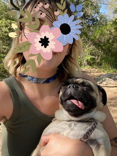 a woman holding a pug in her arms with flowers on it's face