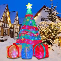 a christmas tree in the snow with presents around it